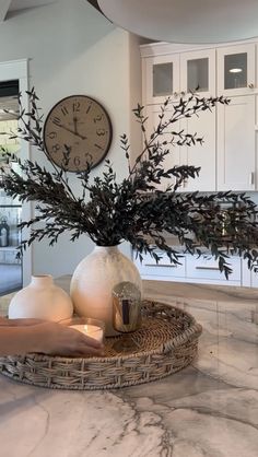 a vase filled with flowers sitting on top of a counter next to a wall clock