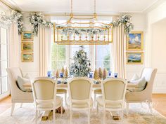 the dining room is decorated for christmas with white furniture