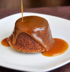 a piece of cake covered in caramel sauce on a white plate with a toothpick sticking out of it