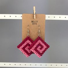 the earrings are made out of legos and have pink squares on each earring