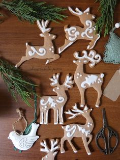 christmas ornaments are arranged on a table with scissors and pine branches in the foreground