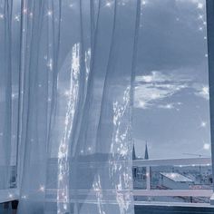 a cat sitting on the window sill in front of a curtain with lights coming from it