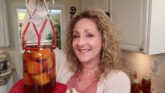 a woman holding a jar full of pickles