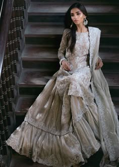 a woman in a long dress sitting on some stairs with her hand on her hip