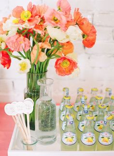 flowers in a vase on a table with empty bottles and straws next to them