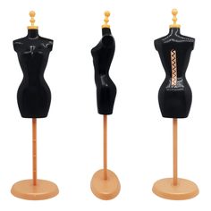 three black mannequins on wooden sticks with gold accents