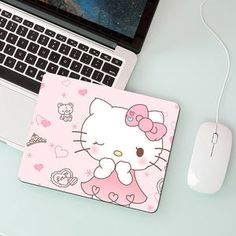 a hello kitty mouse pad sitting next to a laptop