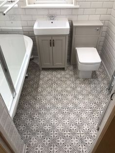 a white toilet sitting next to a bath tub in a bathroom under a sink window