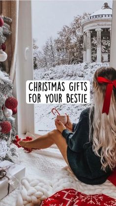 a woman sitting on top of a bed in front of a christmas tree with the words christmas gifts for your bestie