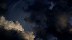 an airplane is flying in the sky with dark clouds behind it and sun peeking through