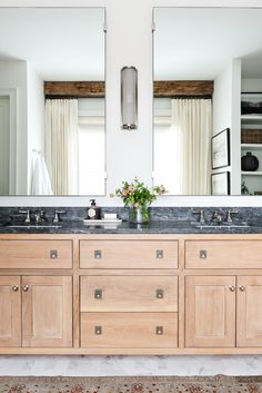 a bathroom with double sinks and large mirrors on the wall above it is decorated in neutral colors