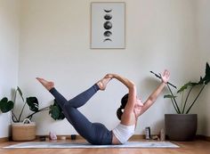 a woman is doing yoga in the middle of a room with potted plants on the wall