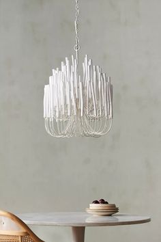 a white chandelier hanging from the ceiling over a table with plates on it