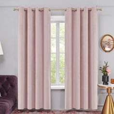 a living room with pink curtains and a purple couch in front of a window that has gold accents