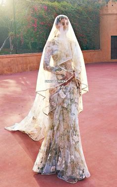 a woman in a wedding dress standing on a red carpet with her veil draped over her head