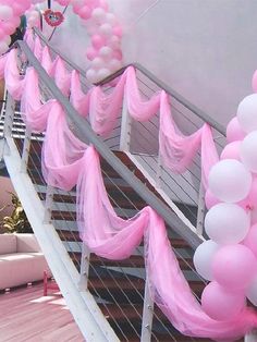 some pink and white balloons are hanging on the stairs