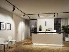 an empty kitchen and dining room with wooden flooring is pictured in this image, there are lights hanging from the ceiling