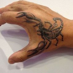 a person's hand with a tattoo on it and a small crab on the wrist