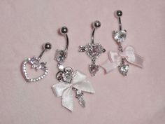 three pairs of dangling belly rings with bows and hearts