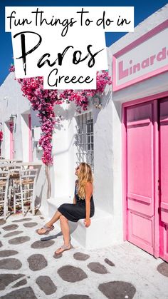 a woman sitting on the side of a building with pink doors and flowers growing out of it