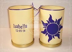 two yellow cups with purple designs on them sitting next to each other, one has a ribbon tied around the top