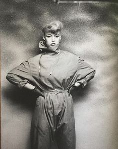 an old black and white photo of a woman with her hands on her hips standing in front of a wall