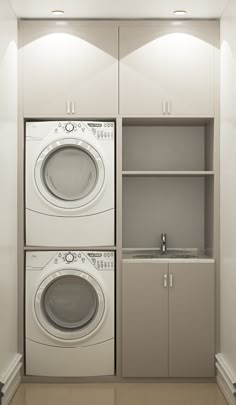 a washer and dryer in a small room with cabinets on the wall behind them