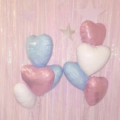 balloons in the shape of hearts and stars on a pink wallpapered background with streamers