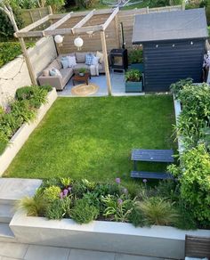 a small backyard with grass and flowers in the center, an outdoor seating area on the other side