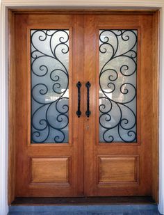 a pair of double doors with glass panels and wrought iron designs on the front door