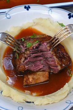 a plate with mashed potatoes, meat and gravy on it next to a fork