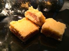 three pieces of cake sitting on top of a black plate next to some ice cubes