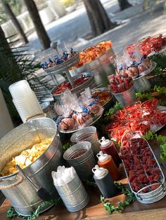 a table topped with lots of food on top of metal buckets filled with condiments