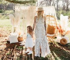 a mother and daughter standing in front of a bohouncy backdrop with feathers