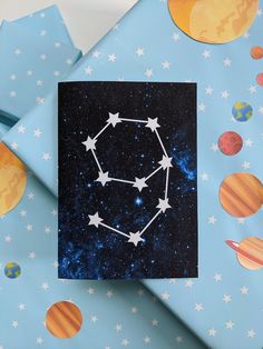 a card with the zodiac sign on it sitting next to some space themed wrapping paper