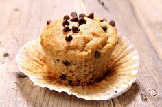 a muffin sitting on top of a white paper cupcake wrapper covered in chocolate chips