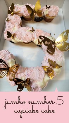 a pink cupcake cake in a box with gold butterflies on it and the number 5