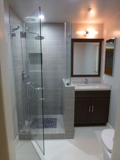 a bathroom with a walk in shower next to a sink and a mirror on the wall