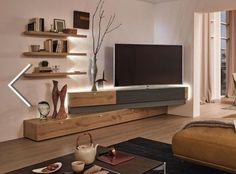 a living room with a large flat screen tv on the wall and shelves above it