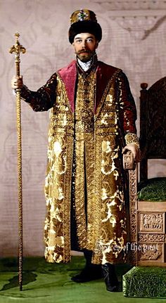 a man dressed in gold and red holding a cane, standing next to a chair