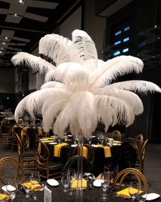 the table is set with black and yellow linens, silverware, and white feathers