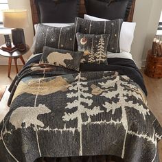 a bed covered in black and white comforter next to a night stand with two lamps