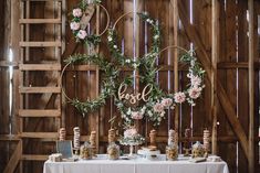 the table is set up with flowers and greenery for an elegant wedding reception at rustic barn