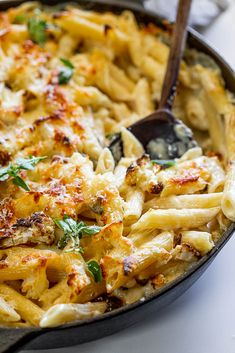 a skillet filled with macaroni and cheese on top of a white table