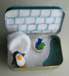 an open tin box with a penguin and fish in it