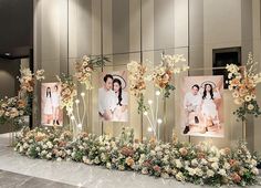 an arrangement of flowers and pictures on display in front of a large wall with mirrors