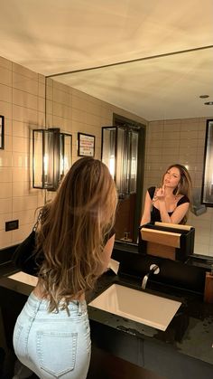 a woman standing in front of a bathroom mirror