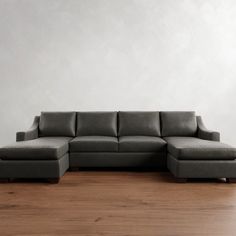 a large gray couch sitting on top of a wooden floor next to a white wall