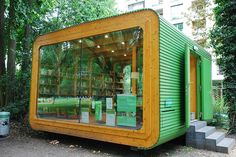 a small green building sitting in the middle of a park