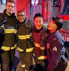 four fire fighters posing for a photo in front of a fire truck